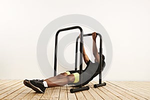 Young black athlete doing bodyweight rows on mobile bars