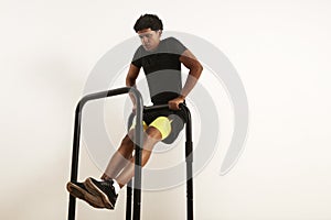 Young black athlete doing bodyweight rows on mobile bars