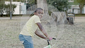 Young black boy cycling in park on warm summer day.