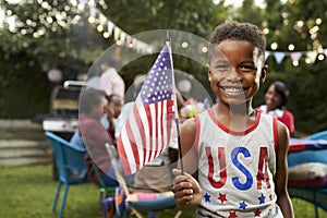 Young black boy holding flag at 4th July family garden party