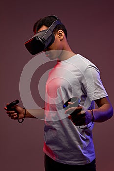 Young black boy with virtual reality glasses is playing a videogame, isolated in studio