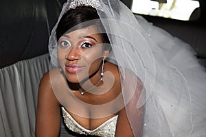 Young black bride looks at the camera and smiles in wedding car