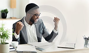 Young black businessman celebrating success with raised arms