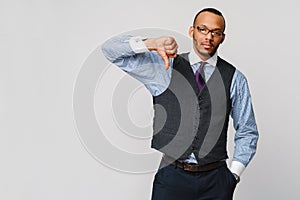 Young black businessman with a dissenting serious dislike expression with thumbs down in disapproval