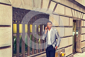 Young black businessman talking on cell phone, walking on street in New York City