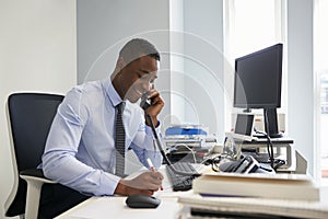 Young black businessman using the phone at his office desk