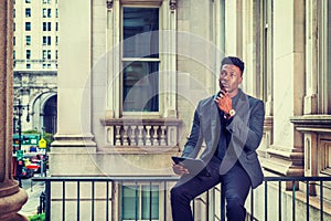 Young black businessman working on tablet computer outside office building