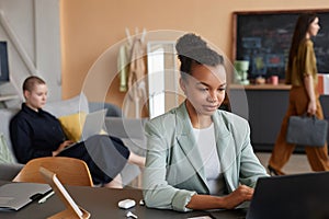 Young black businesswoman using laptop in office with all female team