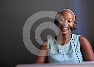 A young Black call centre agent laughs while on a call with headset