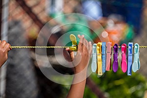 A young black child playing with clothes pegs and a washing line in the garden