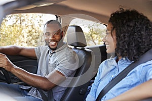 Young black couple in a car looking at each other smiling