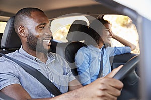 Young black couple in car on a road trip look ahead smiling