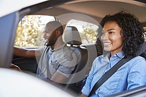 Young black couple in car on a road trip look ahead smiling