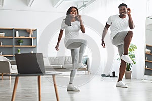 Young black couple doing twist knee to elbow exercise