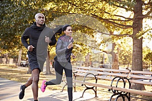 Young black couple jogging in a Brooklyn park, three quarter len photo