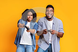 Young black couple with joysticks competing in video games with each other