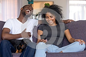 Young black couple with pet have fun watching video online