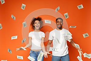 Young black couple standing under money banknotes shower