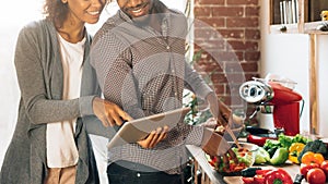 Young black couple using digital tablet in kitchen