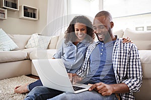 Young black couple using laptop sitting on the floor at home photo