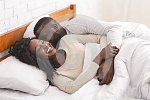 Young black couple waking up in bed in the morning