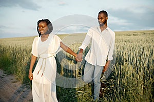 Young black couple walking through green field