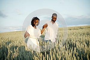 Young black couple walking through green field