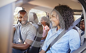 Young black family in a car on a road trip smiling