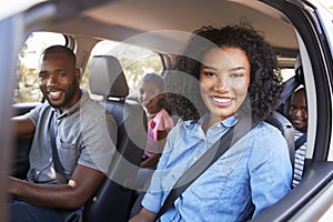 Young black family in a car on a road trip smiling to camera