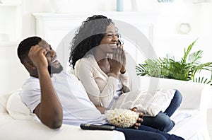 Young black family couple watching comedy movie on tv