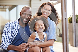 Young black family embracing outdoors and smiling at camera