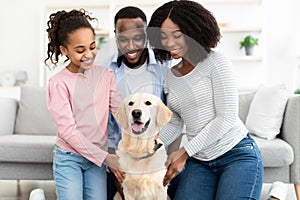 Young black family hugging with dog posing at home