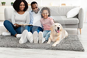 Young black family reading book with dog at home