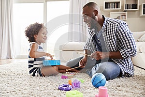 Young black father playing with daughter in the sitting room