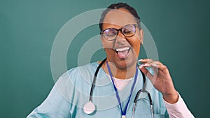 Young Black female doctor dances and laughs wearing scrubs and stethoscope