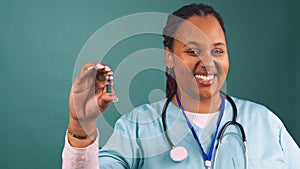 Young Black female doctor talking holding vaccine vial smiling in blue scrubs