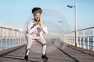 Young Black Female In Sportswear Training With Resistance Loop Band Outdoors