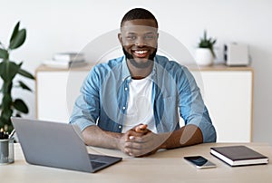 Young Black Freelancer Guy Sitting At Desk With Laptop At Home Office