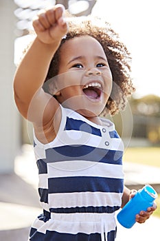 Young black girl blowing bubbles outside her home