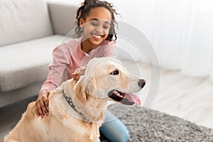 Young black girl having fun with dog at home