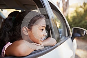 Young black girl looking out of car window smiling, side view