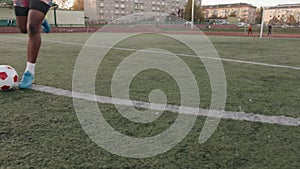 Young black girl in a sleeveless T-shirt and shorts training at the city stadium and practicing ball dribbling technique