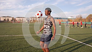 Young black girl in soccer training juggles the ball and throws it from one knee to another. Sports and active lifestyle