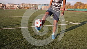 A young black girl training in a city stadium and juggles a soccer ball from one foot to the other. Slow motion