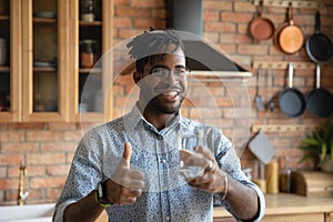 Young black guy hold glass of water show thumb up