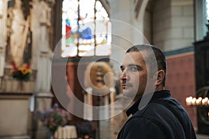 Young black-haired man in a Catholic church enthusiastically sights