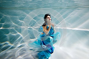 Young black-haired woman in blue dress poses with