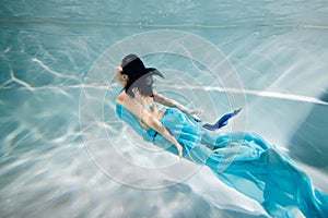 Young black-haired woman in blue dress swims