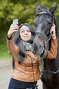 Young black-haired woman makes selfie with horse