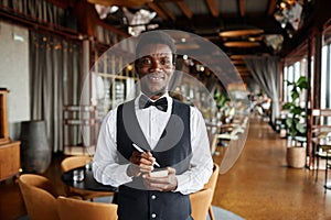 Young Black man as server in restaurant holding notepad ready to take orders